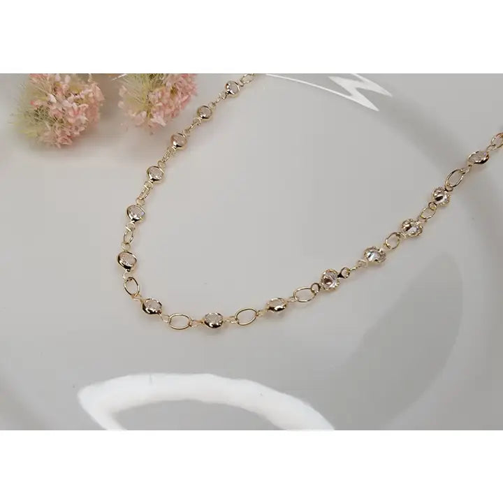 Gold necklace on a white surface with a blurred background