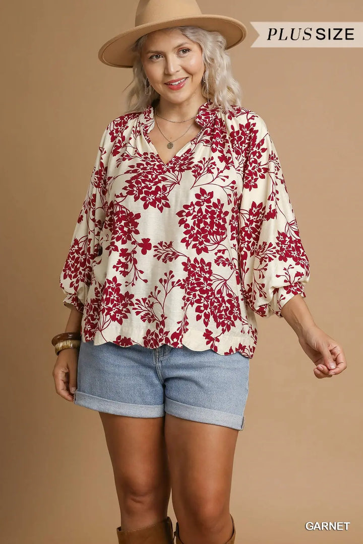 Woman wearing a floral blouse, denim shorts, and a hat on a beige background