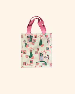 white bag featuring pink and green christmas designs of a tree, gifts, wreath, and bows 