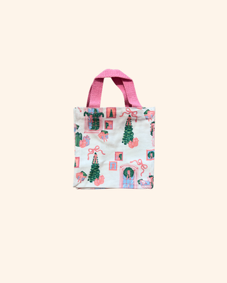 white bag with pink and green designs of trees, gifts, wreaths, and bows