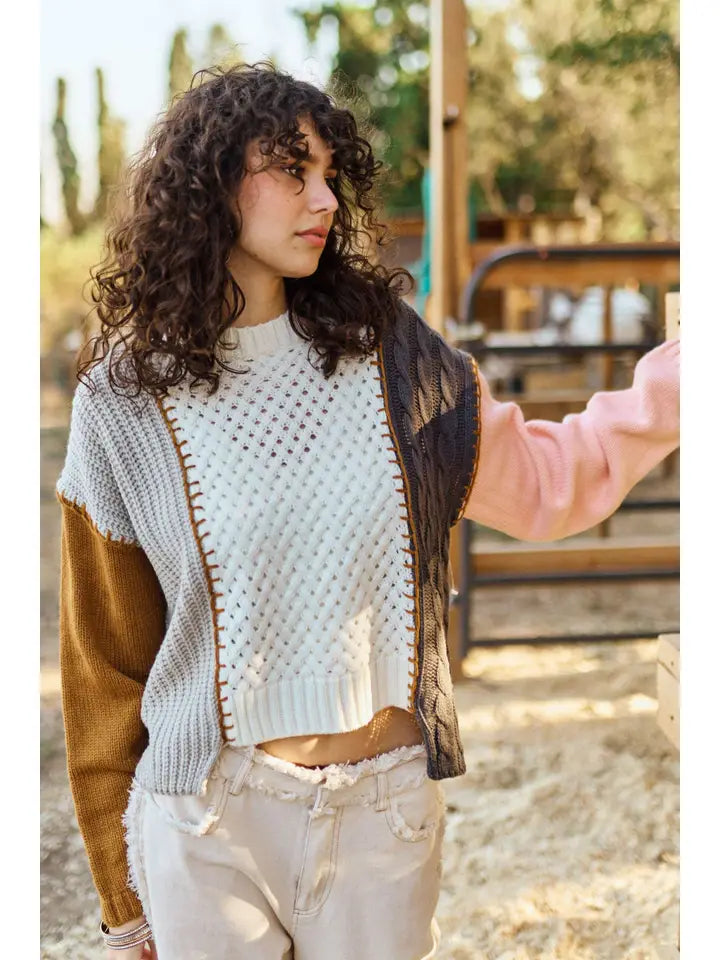 Woman wearing a light blue sweater with brown sleeves outdoors