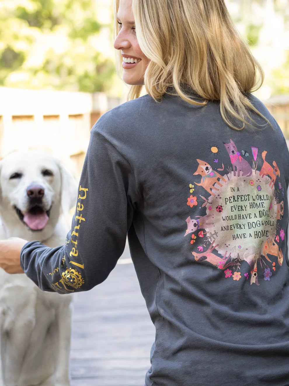 Woman wearing a t-shirt with a dog-themed design, standing next to a white dog.