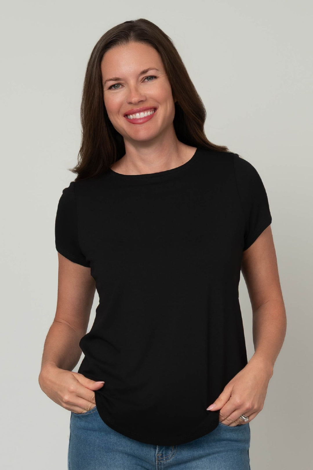 Woman wearing a black t-shirt and blue jeans against a plain background