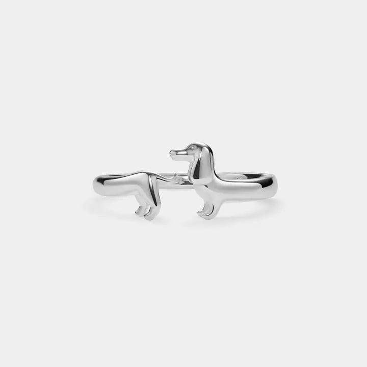 A polished silver ring shaped like a dachshund, shown on a clean, light gray background.