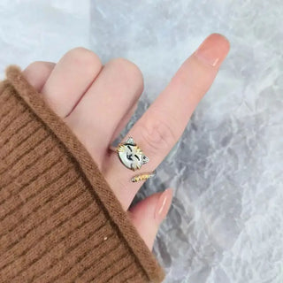 Hand wearing a ring with a sun design on a textured gray background
