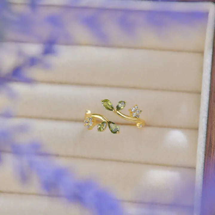 Gold and green leaf-shaped earring on a blurred background