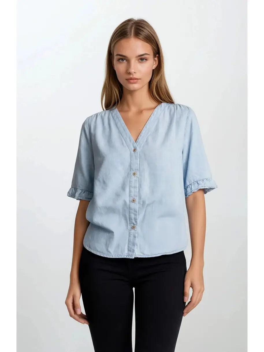 Woman wearing a light blue denim shirt with black pants on a white background