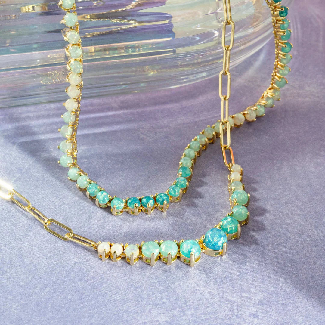 Gold necklace with green gemstones on a textured surface