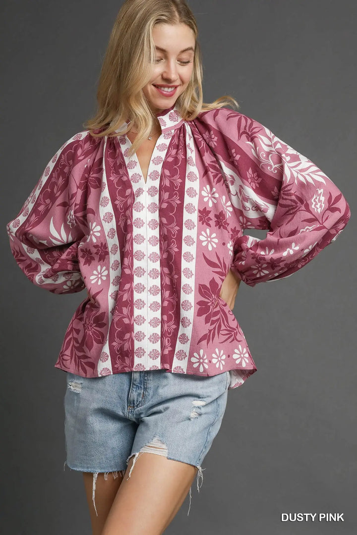 Woman wearing a pink floral blouse with denim shorts on a gray background