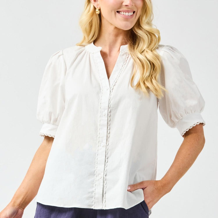 Woman wearing a white blouse with puffed sleeves on a light gray background