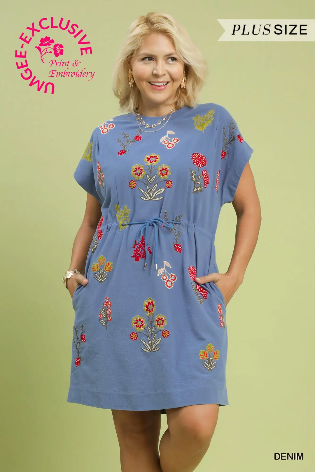 Woman wearing a blue dress with floral embroidery on a green background