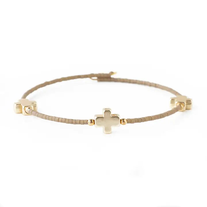 Gold bracelet with a cross charm on a white background