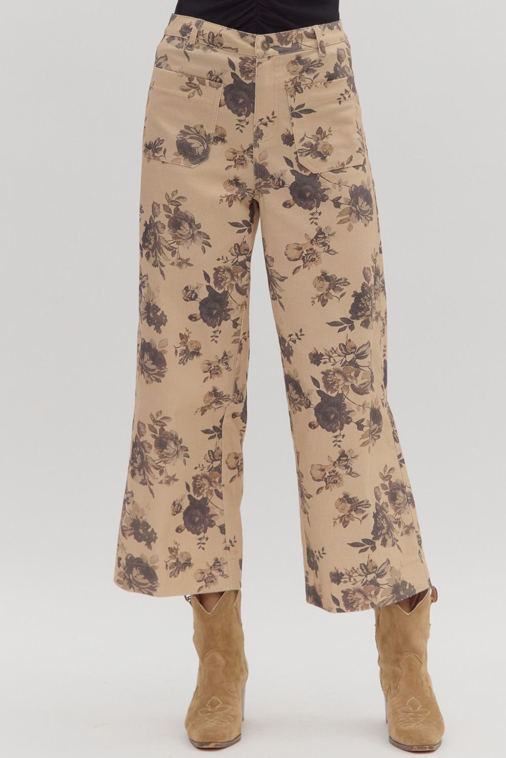 Beige pants with floral pattern worn with brown boots on a white background