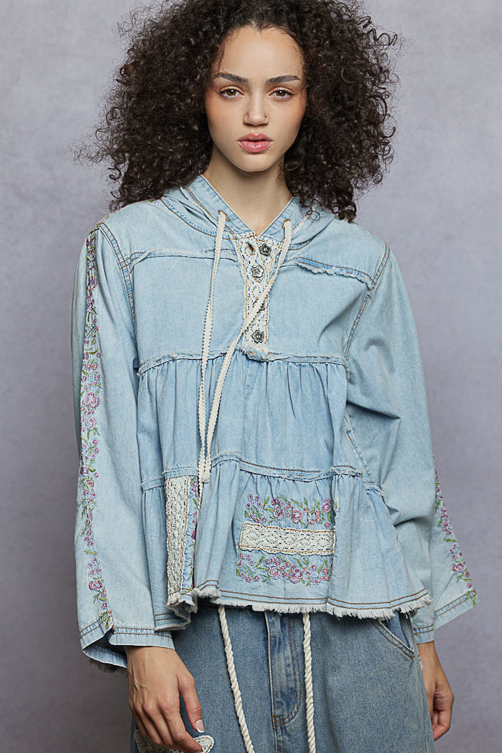 woman wearing light denim colored hoodie top with floral embroidered details