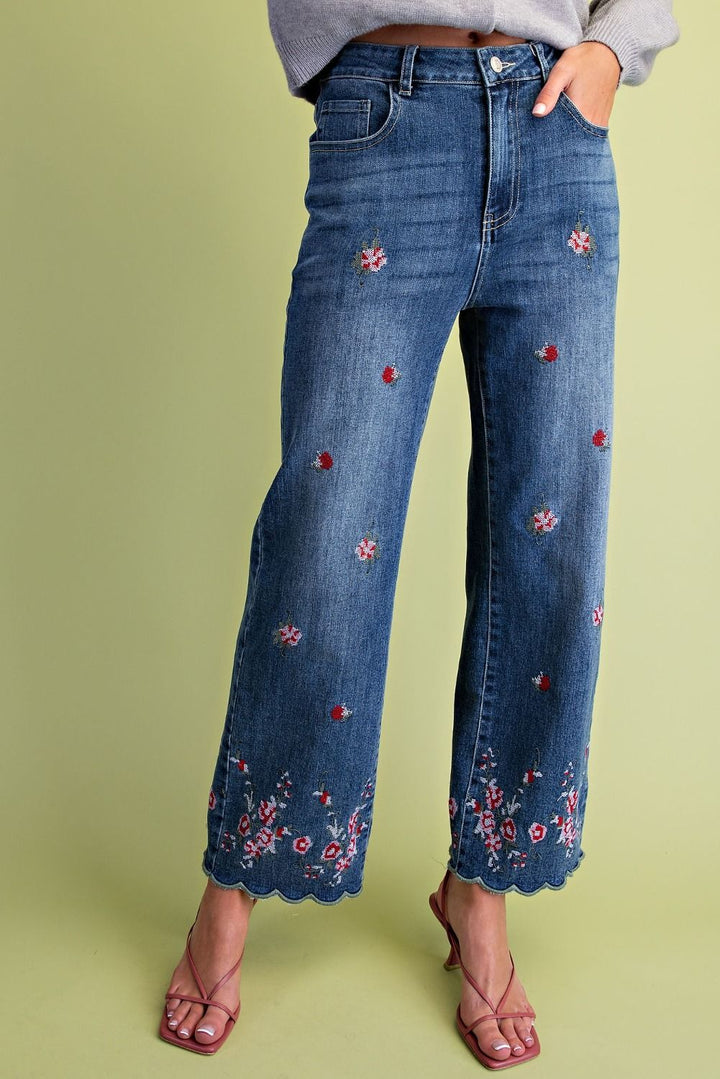 Blue jeans with floral embroidery on a green background