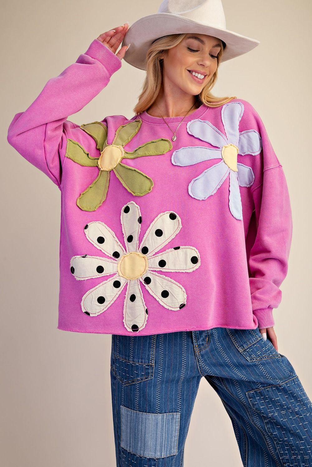 Woman wearing a pink sweatshirt with flower designs on a beige background