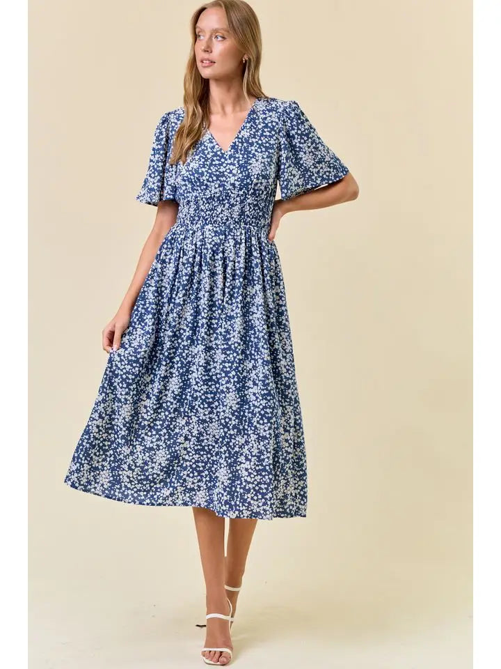 Woman wearing a flowy blue dress with white floral all-over pattern