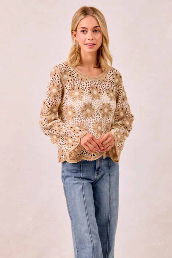 Woman wearing a patterned top and jeans against a plain background