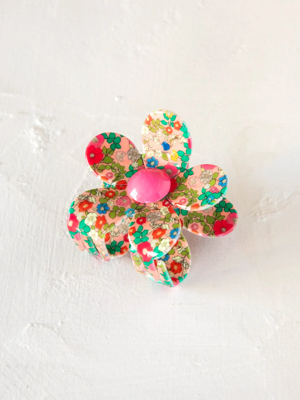 Colorful flower-shaped hair clip on a textured white background