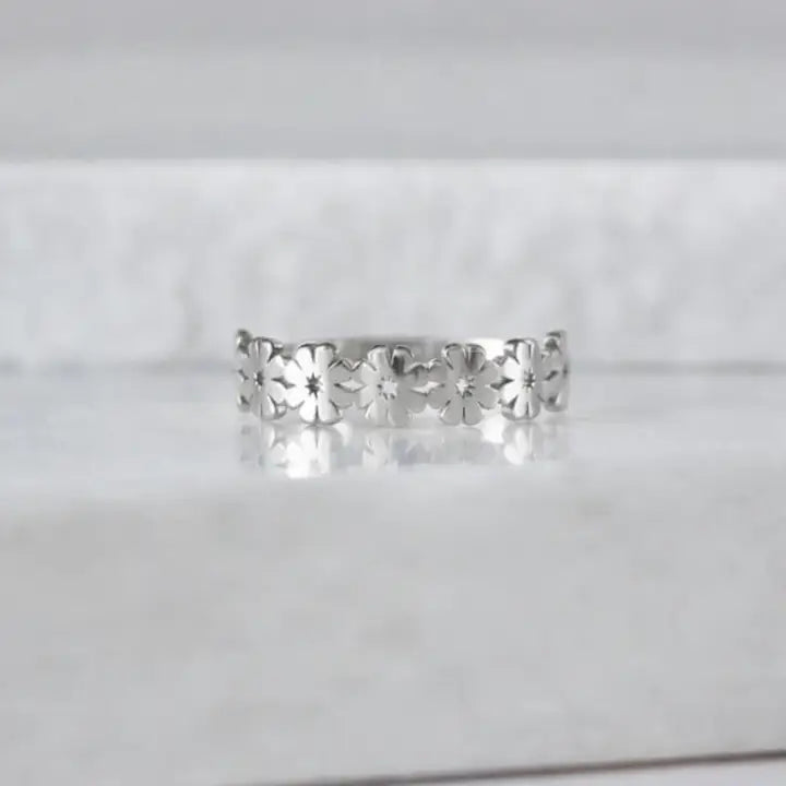 Silver floral ring on a light gray background