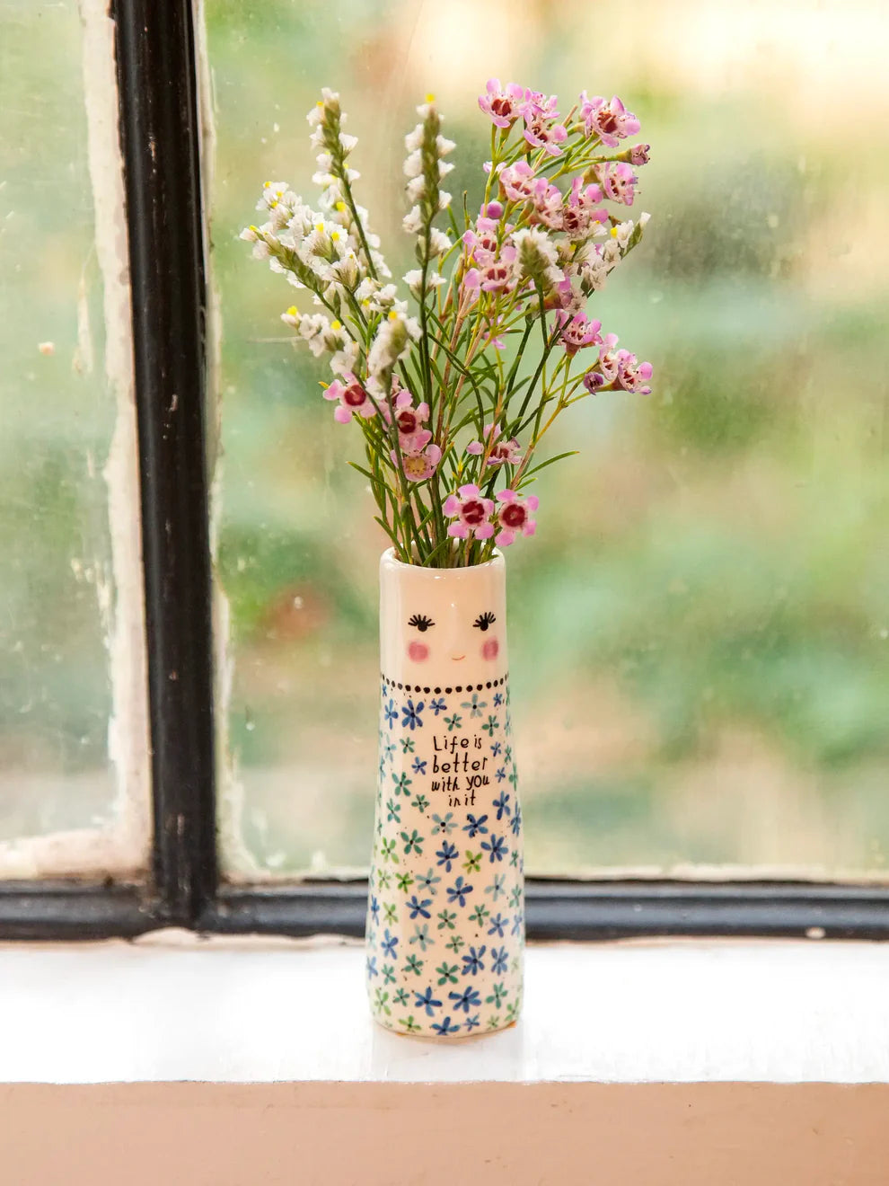 Decorative vase with flowers in front of a window