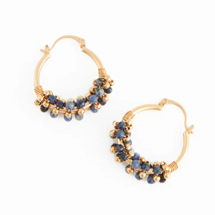 Gold hoop earrings with blue gemstones on a white background