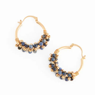 Gold hoop earrings with blue gemstones on a white background