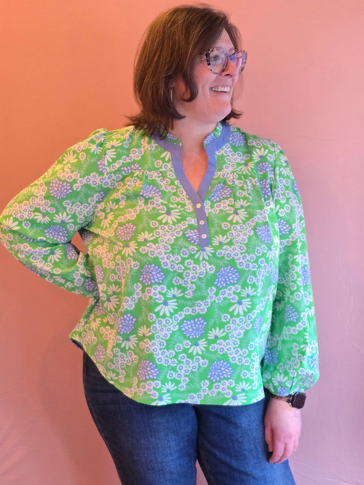 Person wearing a green floral jacket against a pink background