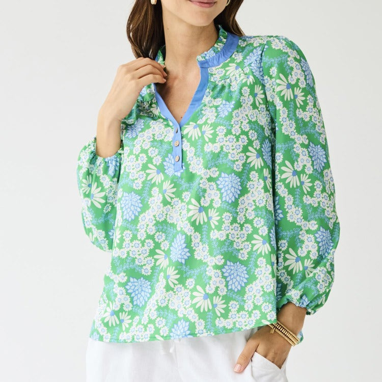 Woman wearing a green floral blouse with blue accents on a white background