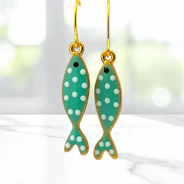 Green fish-shaped earrings with white polka dots on a blurred background