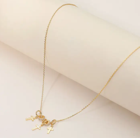 Gold necklace with small charms on a light pink background