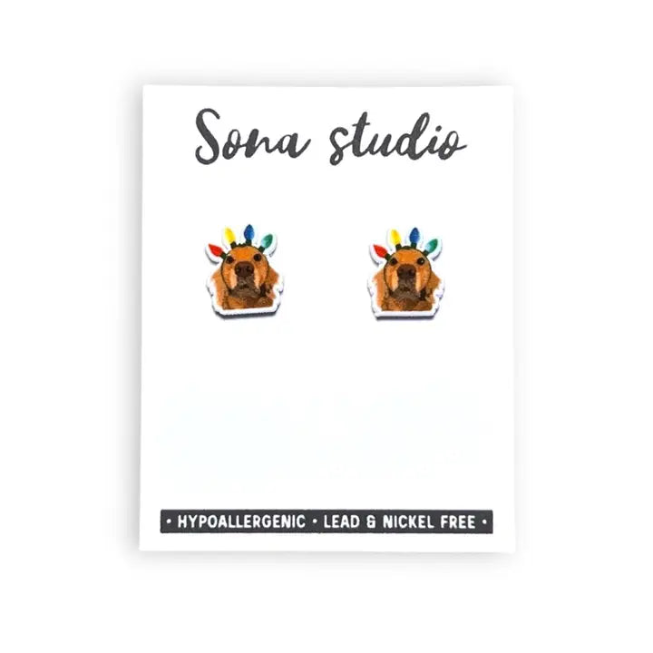 Earrings with a dog design on a white card with 'Sona Studio' branding.