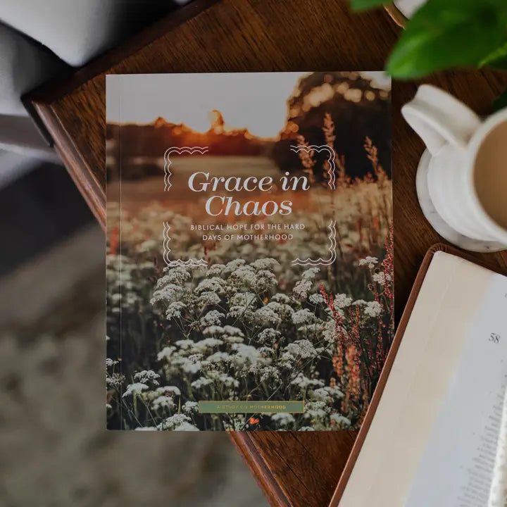 Book titled 'Grace in Chaos' on a wooden surface with a cup of coffee and plant.
