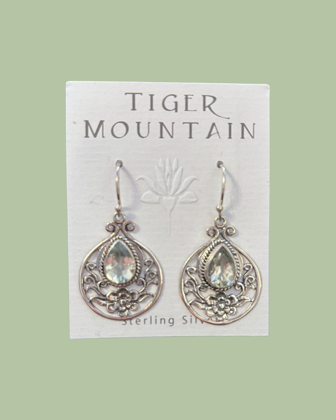 Pair of silver earrings with gemstones on a 'Tiger Mountain' branded card.