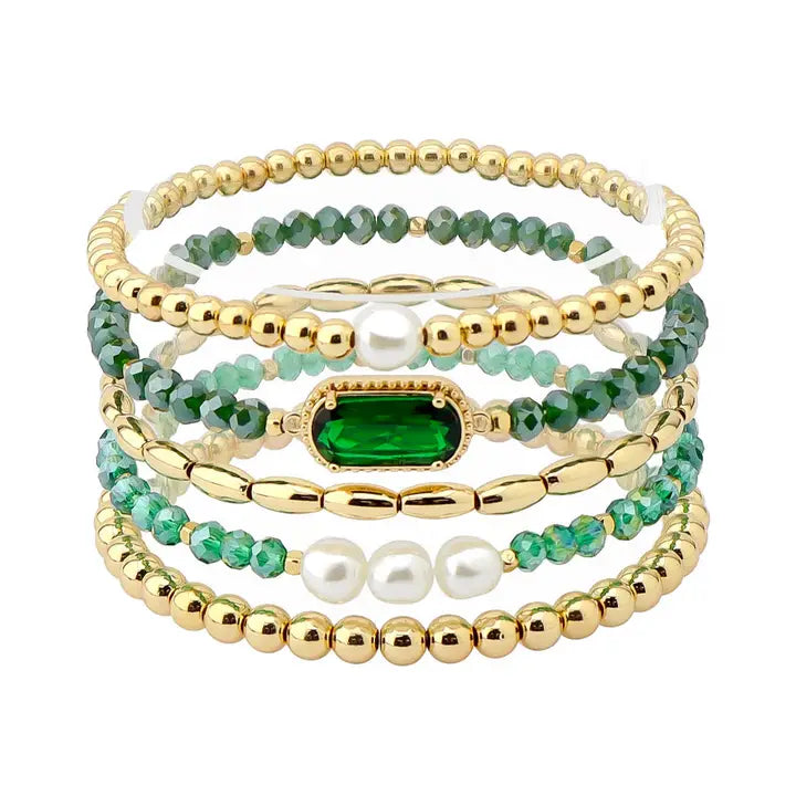 Set of beaded bracelets with gold, green, and pearl accents on a white background