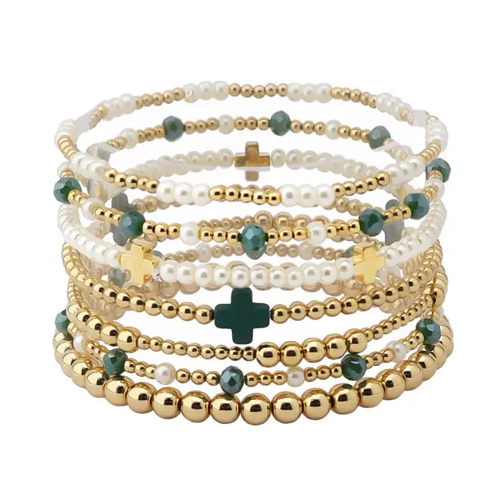Stack of beaded bracelets with gold and green accents on a white background