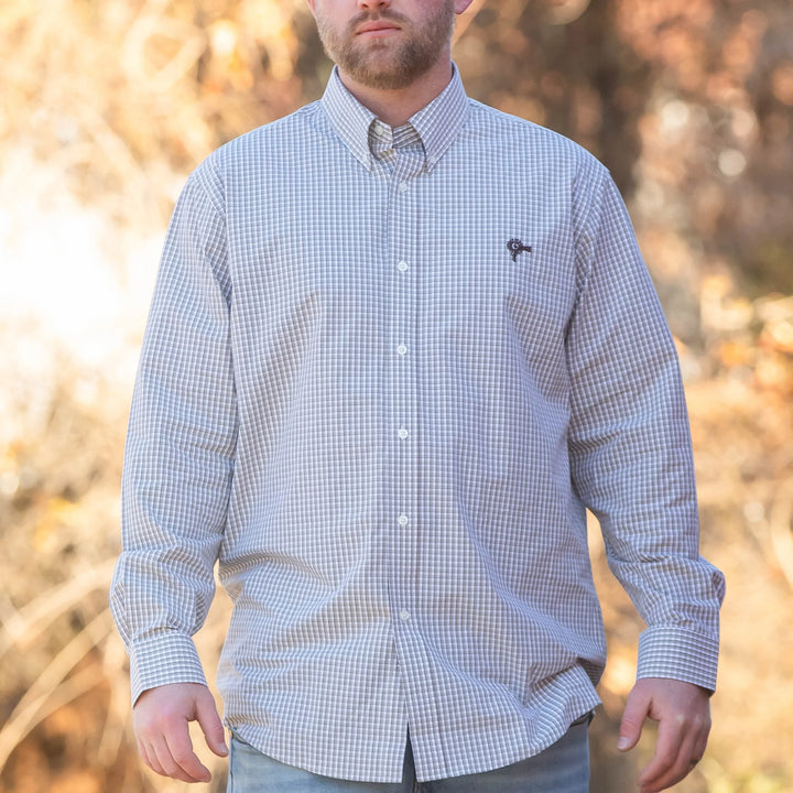 Man wearing a checkered shirt outdoors with a blurred natural background