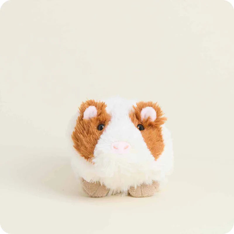 Plush toy guinea pig with brown and white fur on a beige background