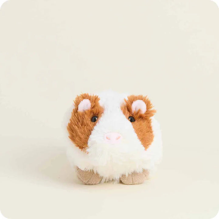 Plush toy guinea pig with brown and white fur on a beige background