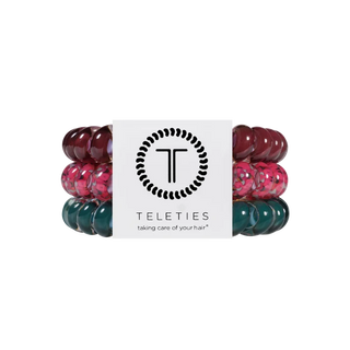 Three Teleties hair elastic bands in burgundy, pink, and teal-green translucent patterns, wrapped around a white paper band with the Teleties logo.