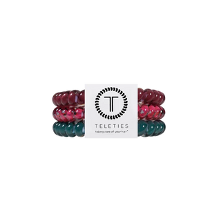 Three beaded stretch bracelets by Teleties, stacked vertically with a white paper band in the center. The top bracelet is dark burgundy, the middle is pink and red marbled, and the bottom is dark teal green marbled.