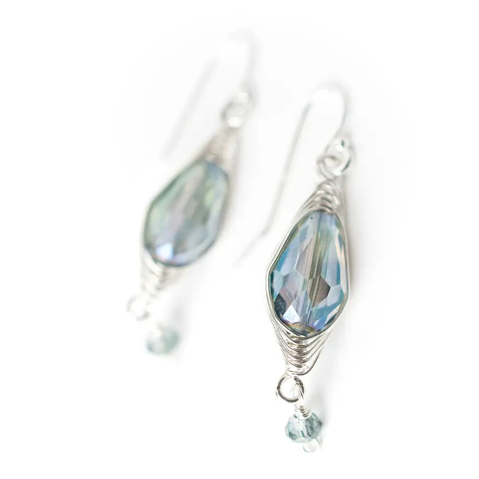 Silver earrings with blue gemstones on a white background