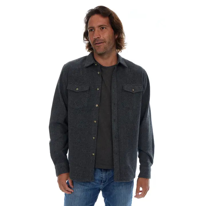 Man wearing a dark gray flannel shirt over a black t-shirt on a white background