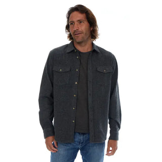 Man wearing a dark gray flannel shirt over a black t-shirt on a white background