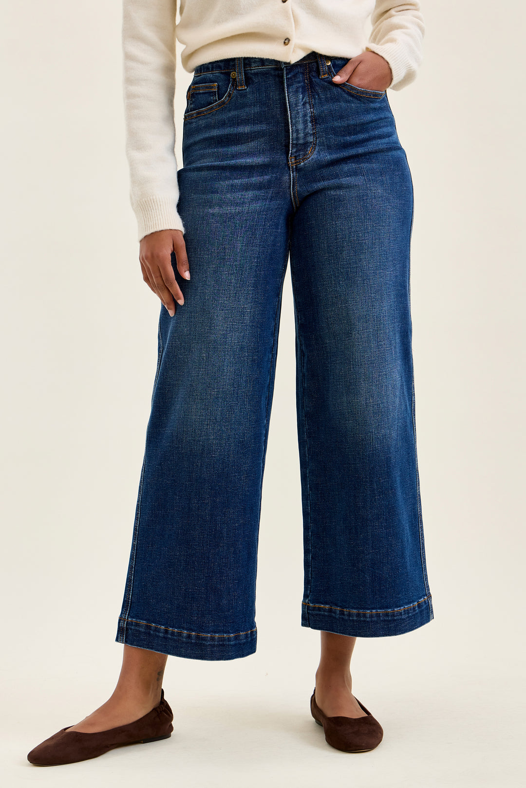 Person wearing blue jeans on a plain background