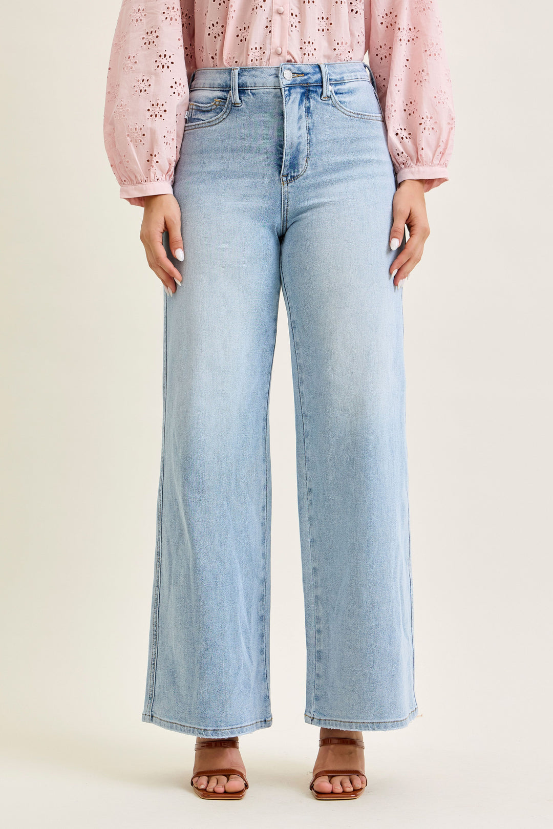 Light blue jeans worn by a person on a beige background