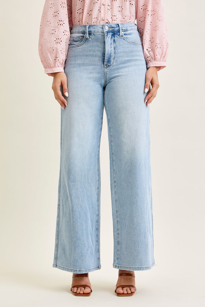 Light blue jeans worn by a person on a beige background