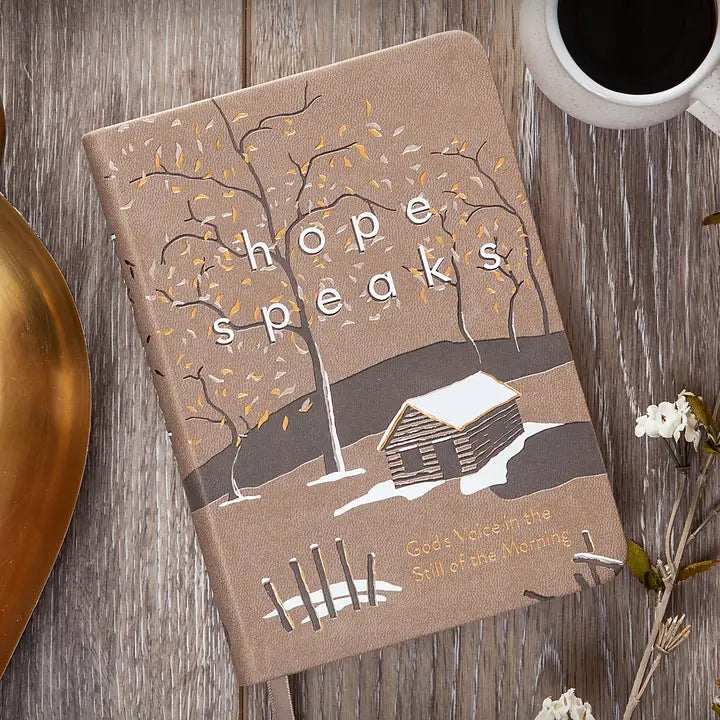 Notebook with 'hope speaks' design on a wooden surface with a cup of coffee.