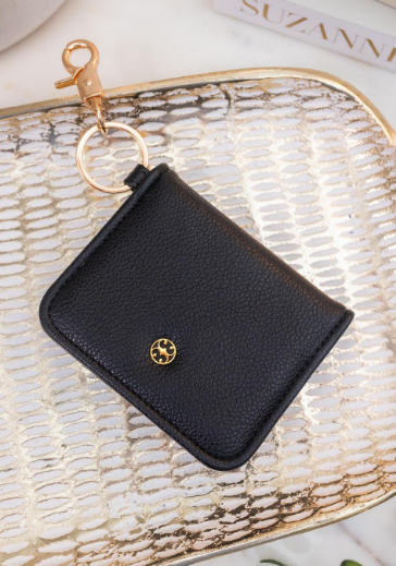 Black wallet with gold clasp and logo on a textured surface