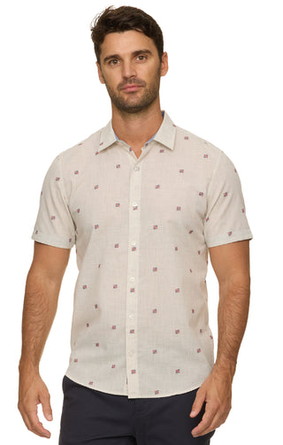 Man wearing a beige short-sleeve shirt with a subtle pattern on a white background